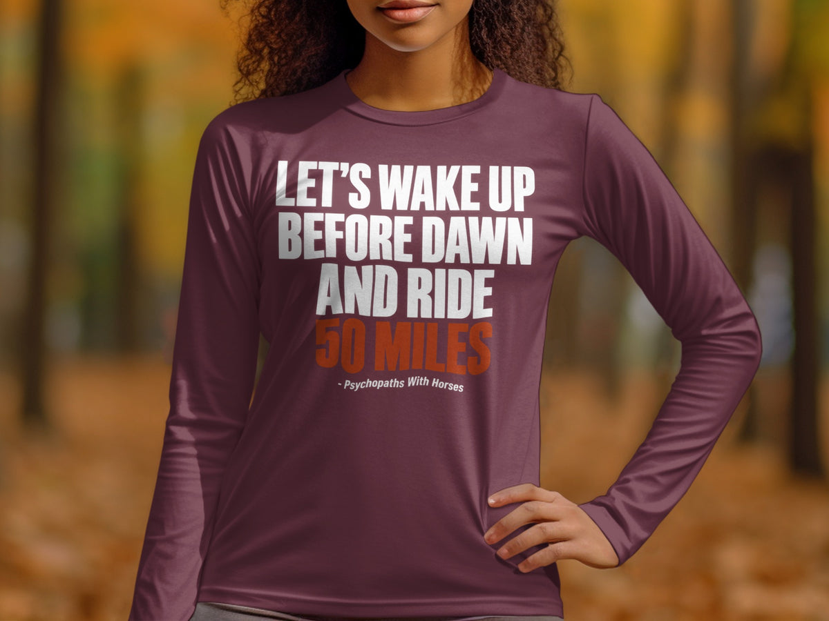 A person wearing a maroon long-sleeve shirt with white and orange text reading Let's wake up before dawn and ride 50 miles.