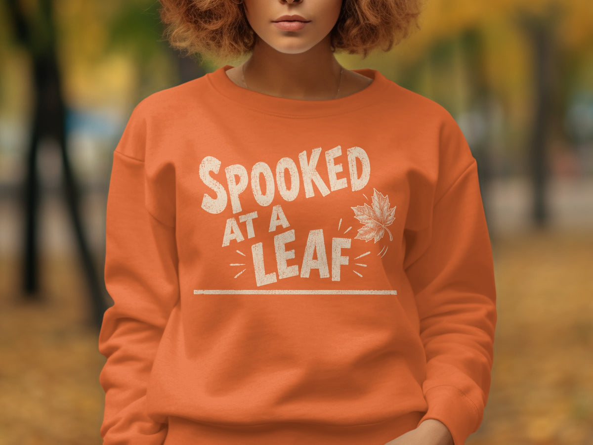 Orange sweatshirt with "SPOOKED AT A LEAF" text and a maple leaf graphic.