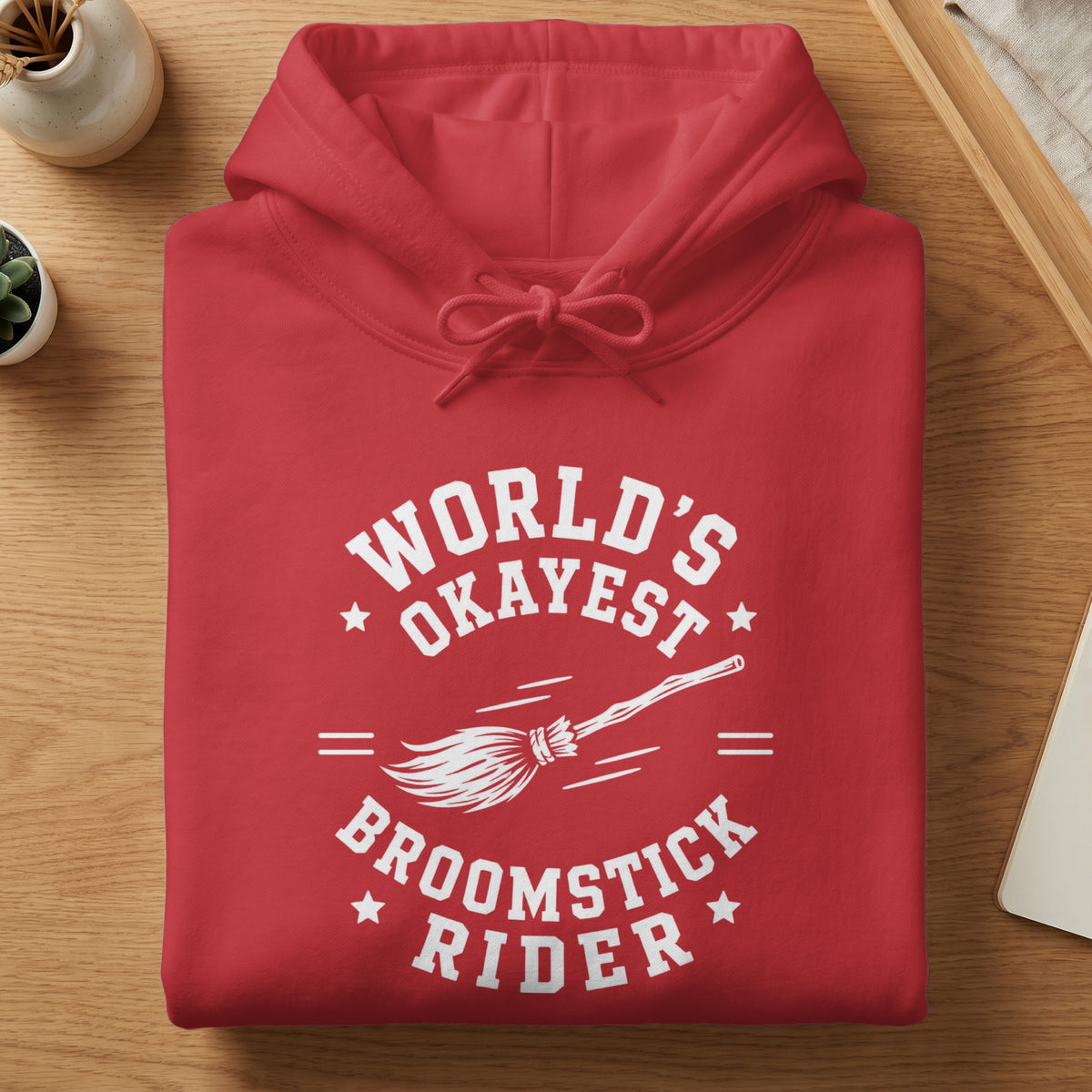 Red hoodie with white text "World's Okayest Broomstick Rider" and a broom graphic.