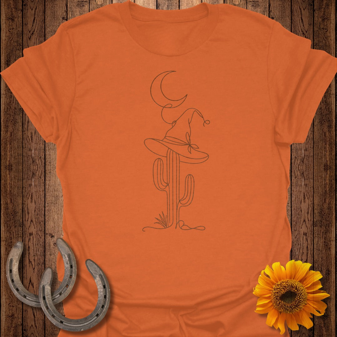 Orange t-shirt with a minimalist line drawing of a cactus wearing a witch hat and a crescent moon.
