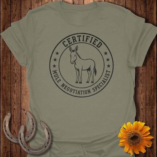 Olive t-shirt with circular graphic reading "CERTIFIED MULE NEGOTIATION SPECIALIST" and a mule.