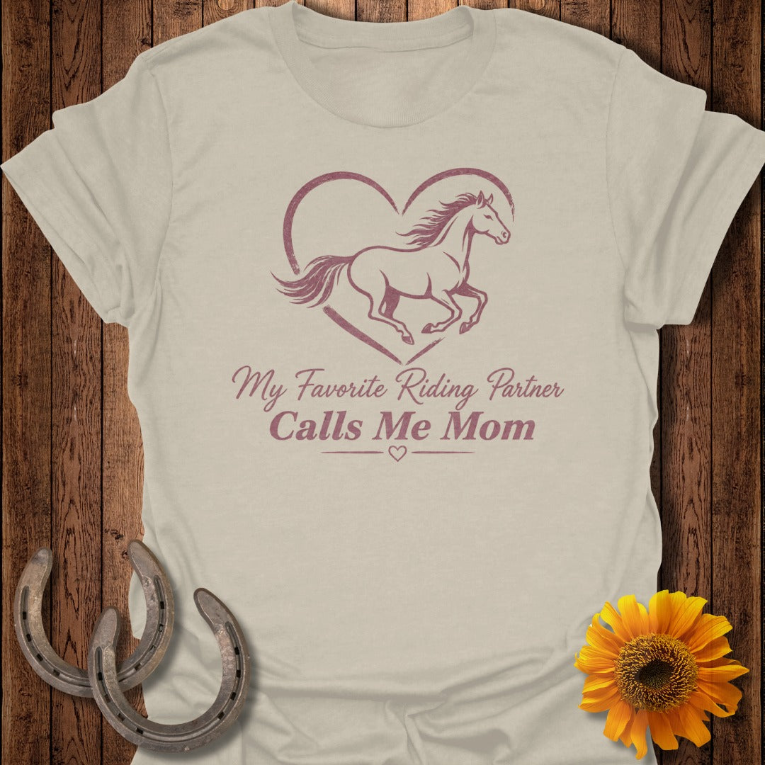 Light brown t-shirt with a horse inside a heart and "My Favorite Riding Partner Calls Me Mom" text.