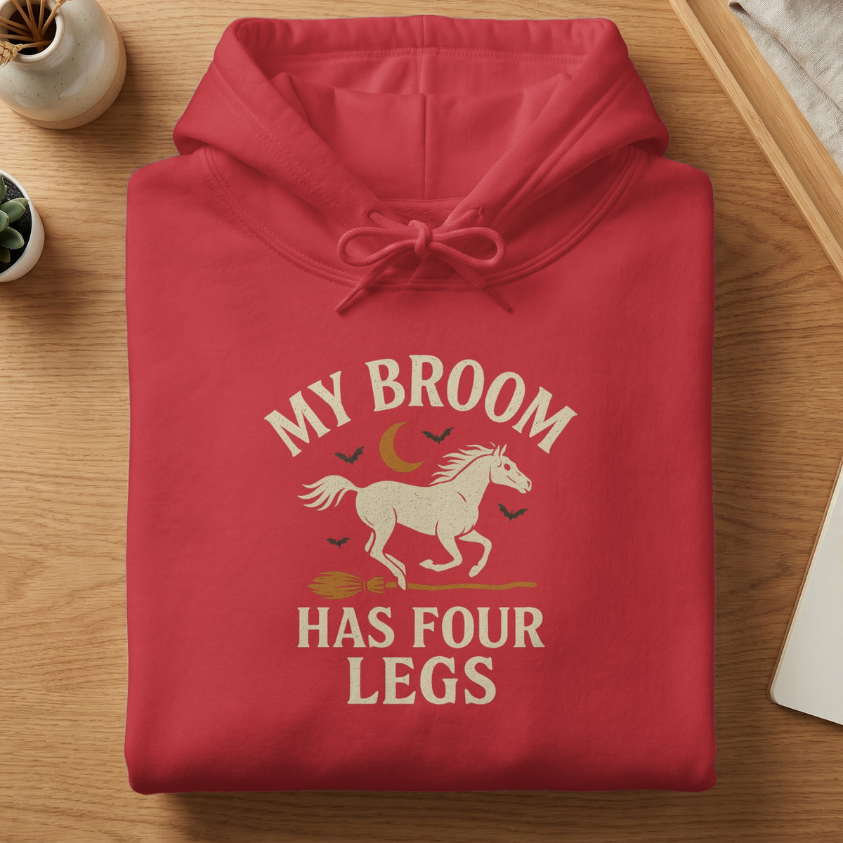 Red hoodie with "My Broom Has Four Legs" text, horse, broom, and moon graphic.
