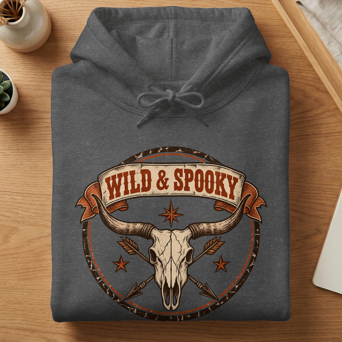 Dark grey hoodie with a graphic of a longhorn skull, arrows, and "WILD & SPOOKY".