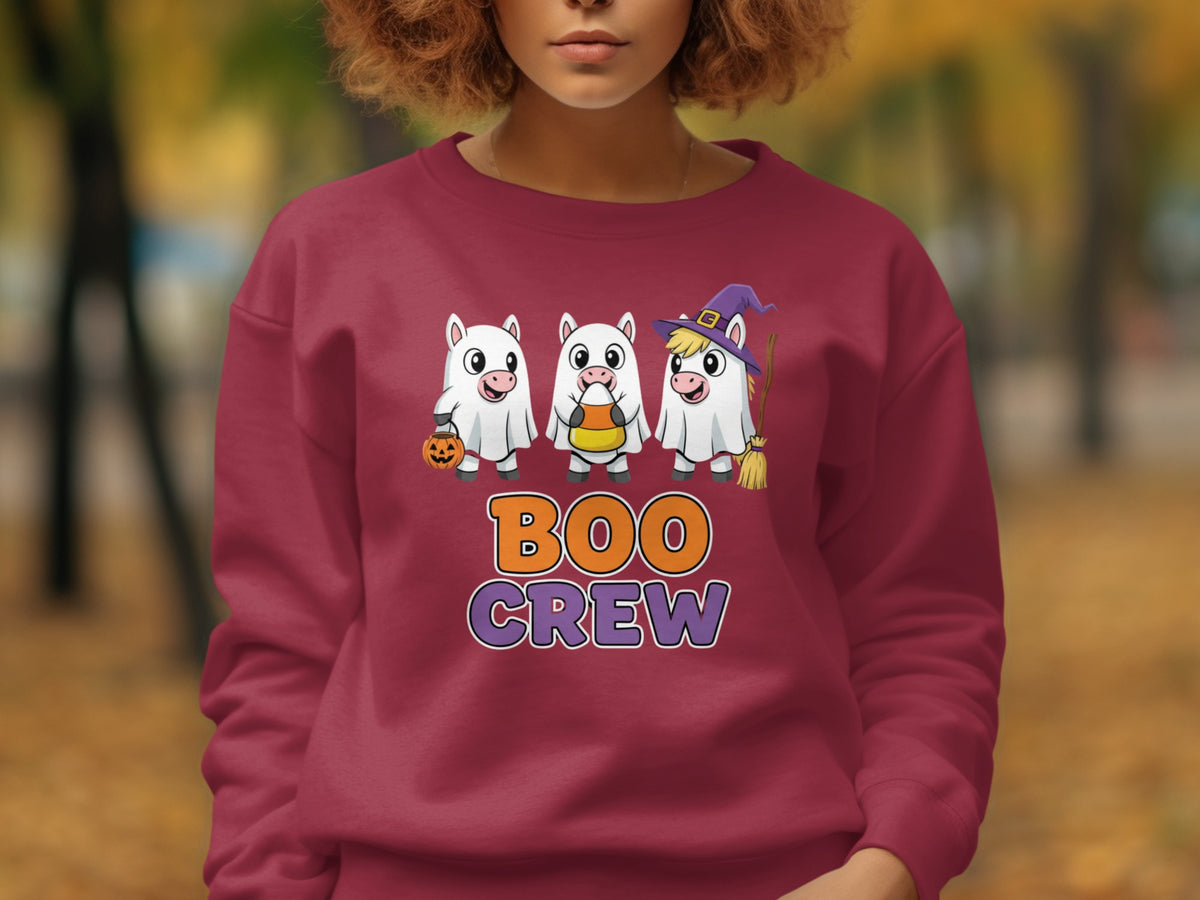 Three unicorns in ghost costumes hold Halloween treats and a broom.