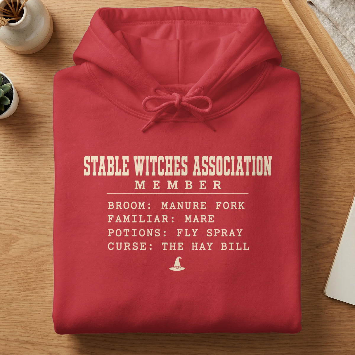 Red hoodie with "Stable Witches Association Member" text and list.