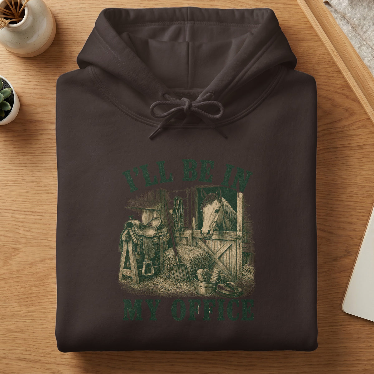 Brown hoodie with green graphic of a horse in a stable, saddle, and text "I'LL BE IN MY OFFICE".