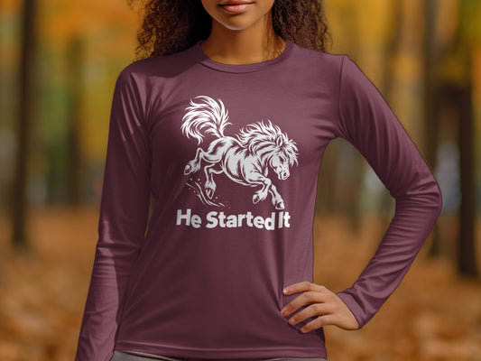 A person wearing a maroon long-sleeve t-shirt featuring a white graphic of a galloping horse and the text "He Started It".