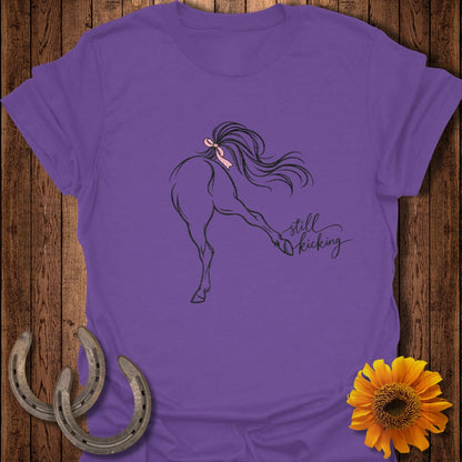Purple t-shirt with black line drawing of a horse kicking and "still kicking" text.