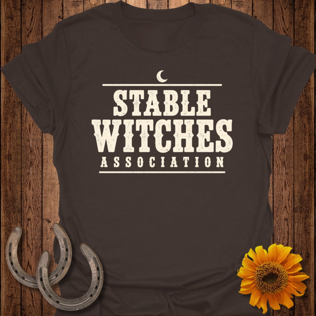 Brown t-shirt with "Stable Witches Association" text, horseshoes, and sunflower.