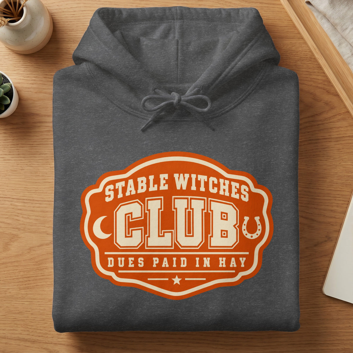 Dark grey hoodie with "Stable Witches Club Dues Paid in Hay" graphic.