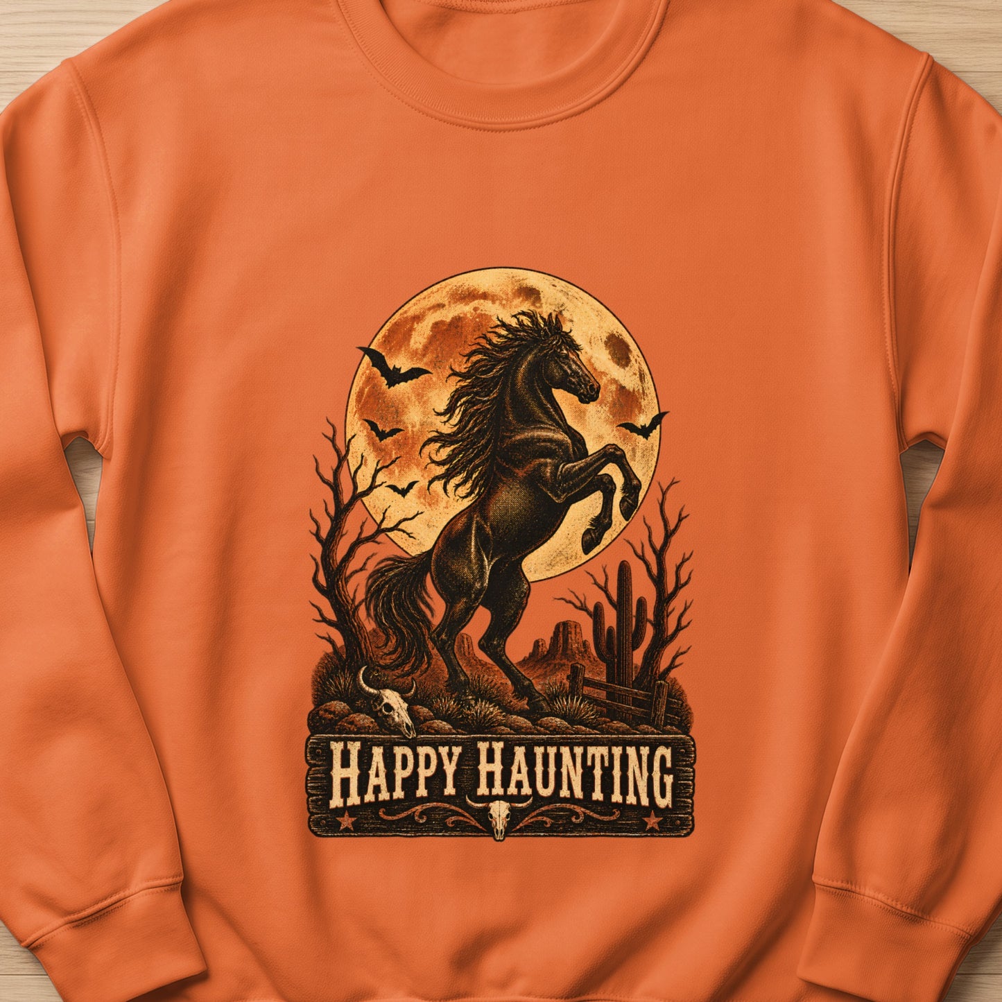 Orange sweatshirt with a rearing black horse, moon, bats, and text "Happy Haunting".