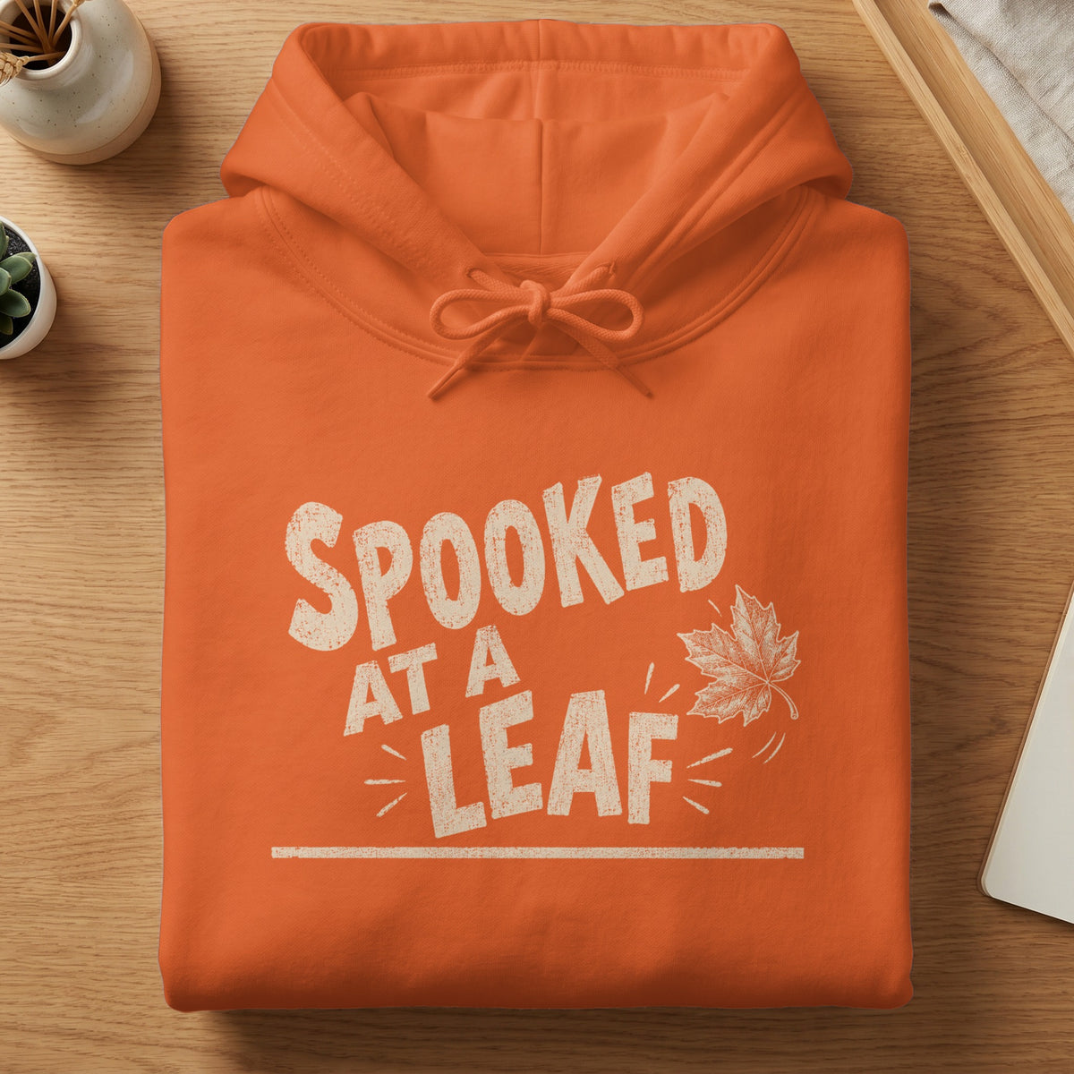 Orange hoodie with "SPOOKED AT A LEAF" text and a maple leaf graphic.