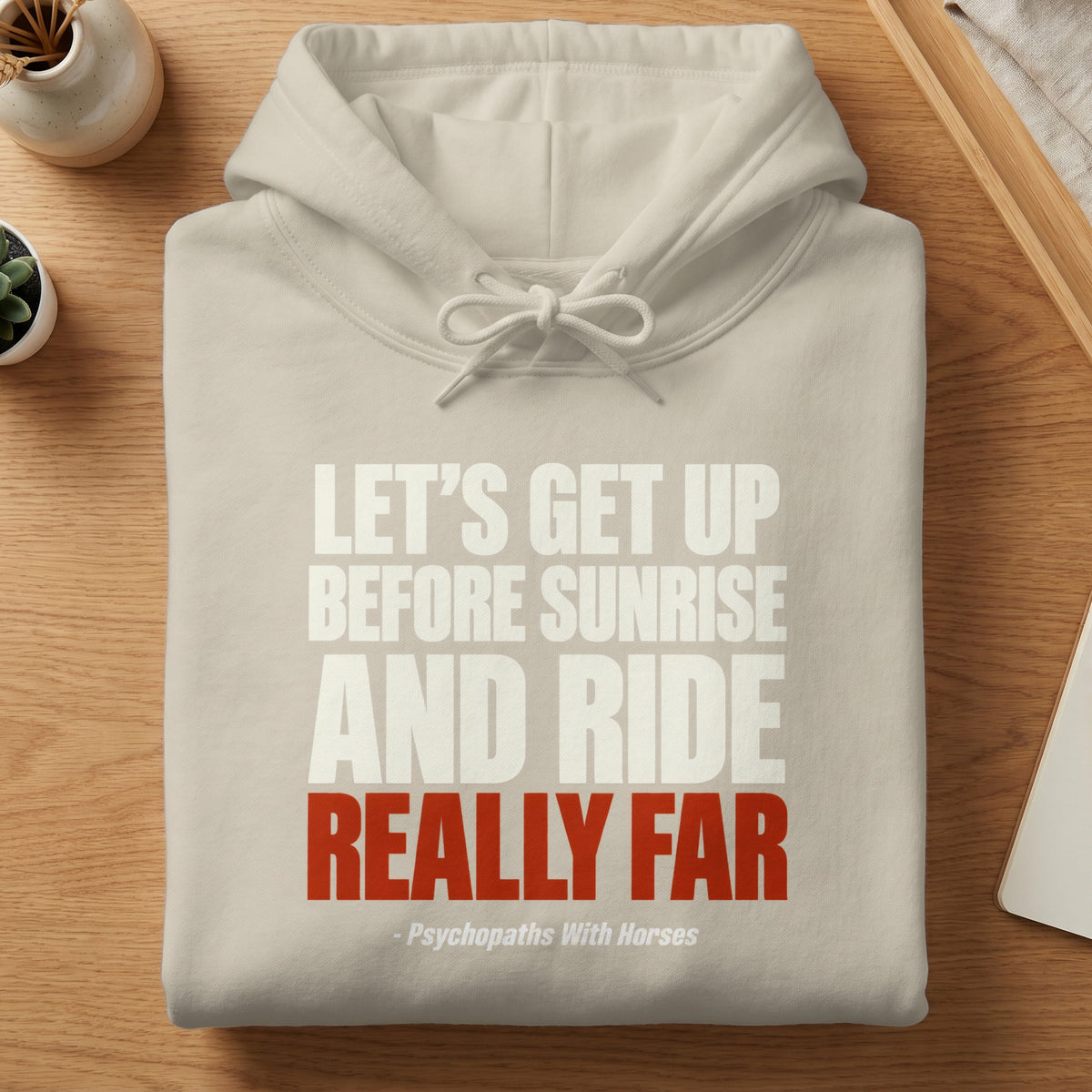 A beige hooded sweatshirt featuring white and red text stating, "Let's get up before sunrise and ride really far - Psychopaths With Horses."