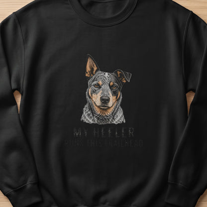Black sweatshirt with an illustration of a heeler dog and text "MY HEELER RUNS THIS TRAILHEAD".