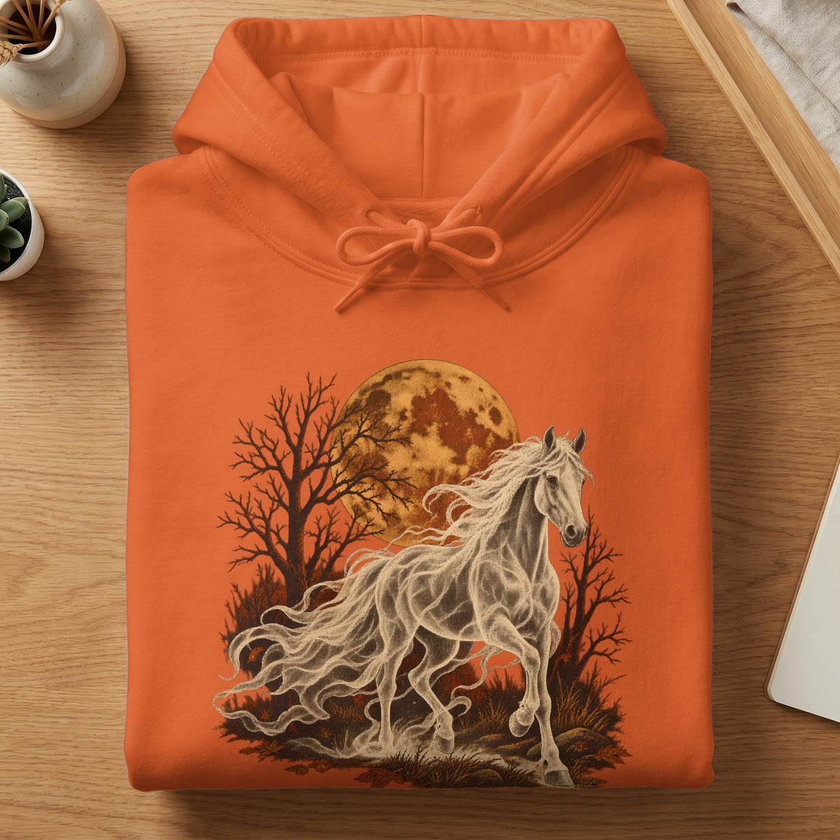 Orange hoodie with a white spectral horse, moon, and trees graphic.