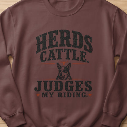 Brown crewneck sweatshirt with distressed "Herds Cattle. Judges My Riding." text and dog graphic.