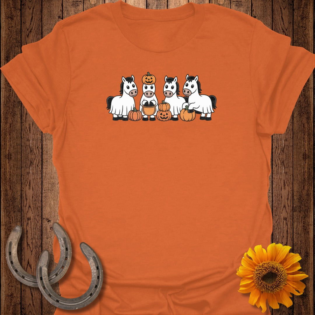 Four horses wearing ghost costumes stand with pumpkins on an orange shirt.