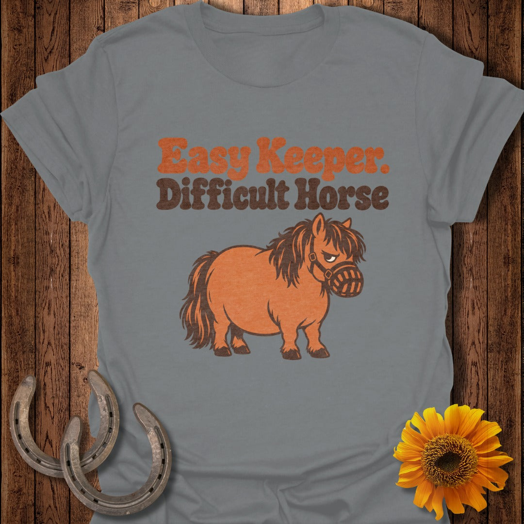 Grey t-shirt with "Easy Keeper. Difficult Horse" text and a cartoon pony wearing a muzzle.
