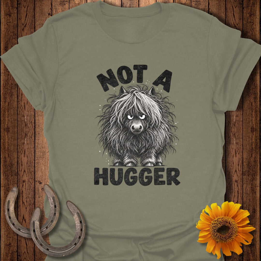 Olive green t-shirt with a graphic of a shaggy, grumpy highland cow and the text NOT A HUGGER.
