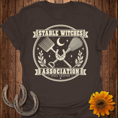 Brown t-shirt with "Stable Witches Association Local Chapter" text and occult imagery.