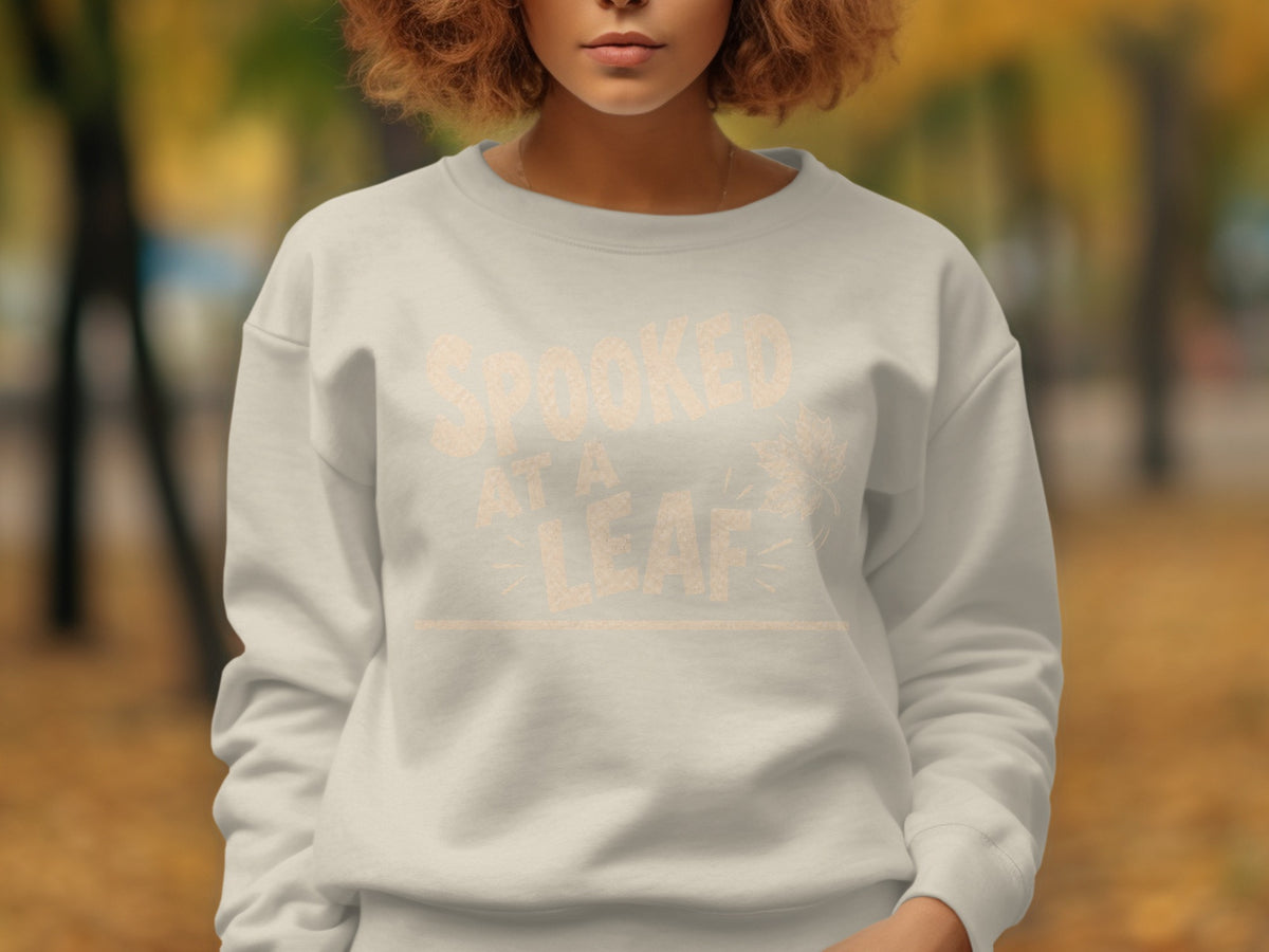 Light grey sweatshirt with "Spooked At A Leaf" text and autumn leaf graphic.