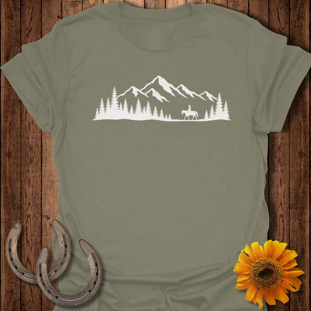 White silhouette of a person on horseback in front of a mountain range and pine trees.