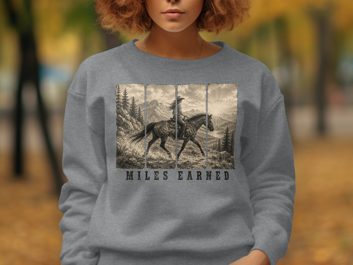 Front of grey sweatshirt with vintage cowboy riding horse graphic and text "MILES EARNED".