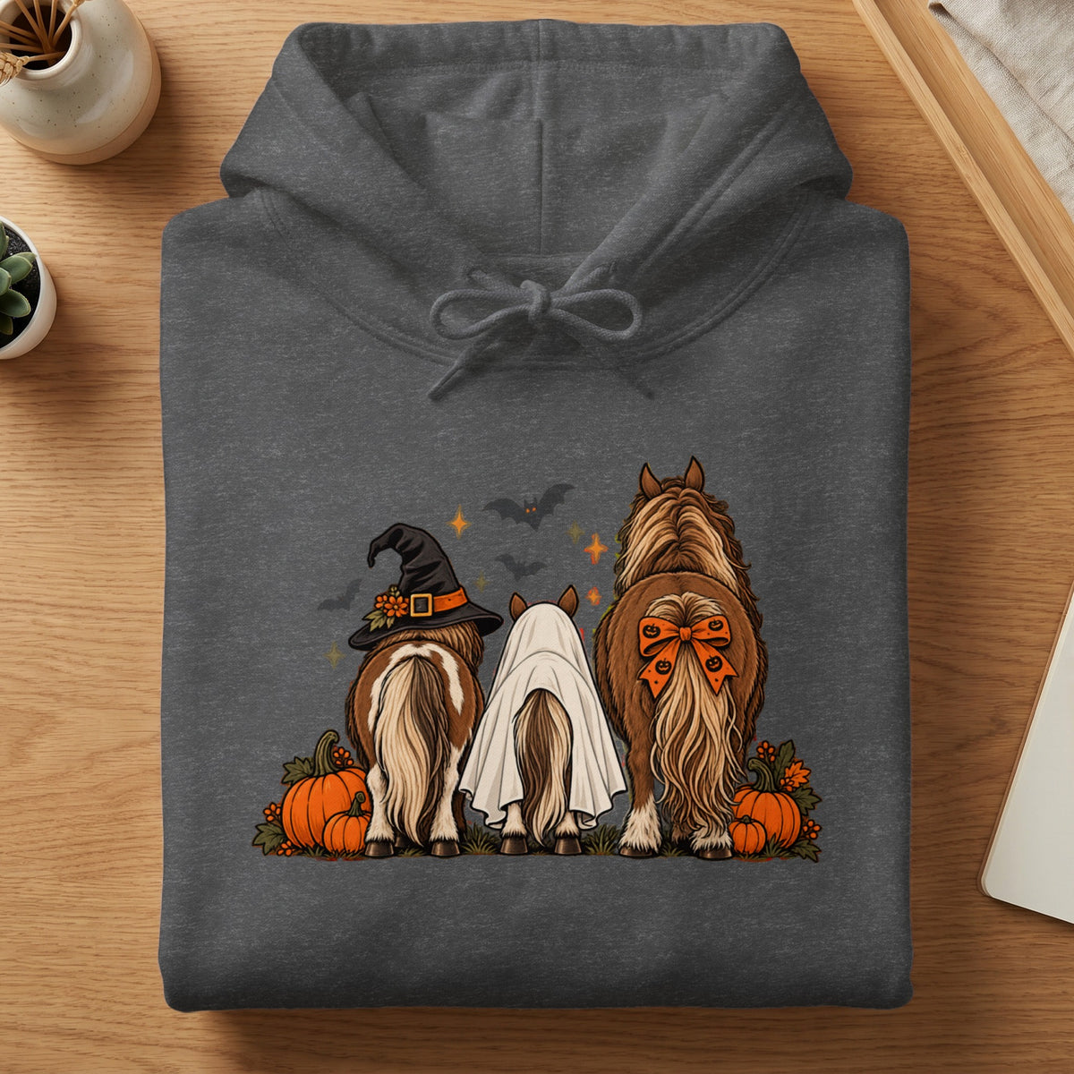 Three horses dressed for Halloween, one in a witch hat, one in a ghost costume, one with a bow.